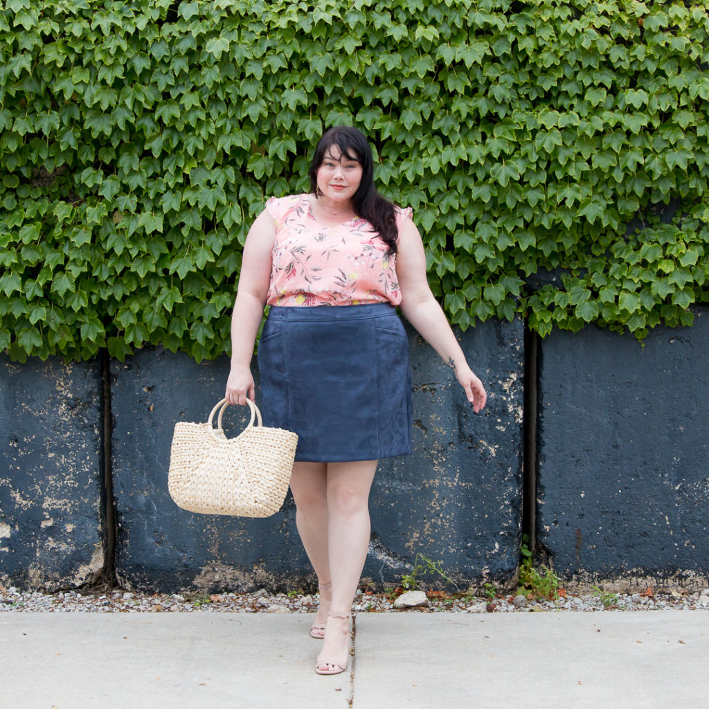 Plus size blogger Amber from Style Plus Curves wears a pink top with a gray skirt for a late summer outfit.