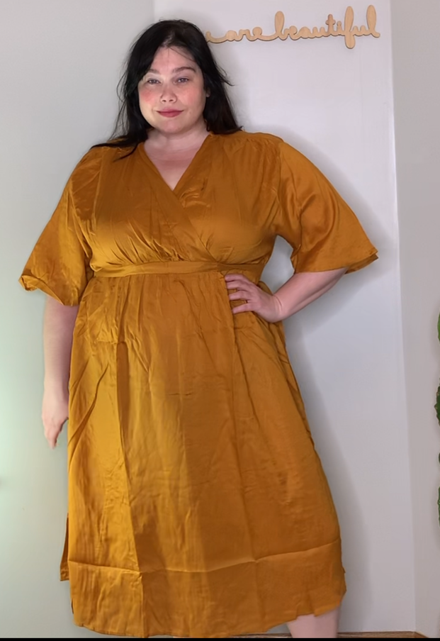 Amber from Style Plus Curves wears a plus size dress in a rich orange color. 