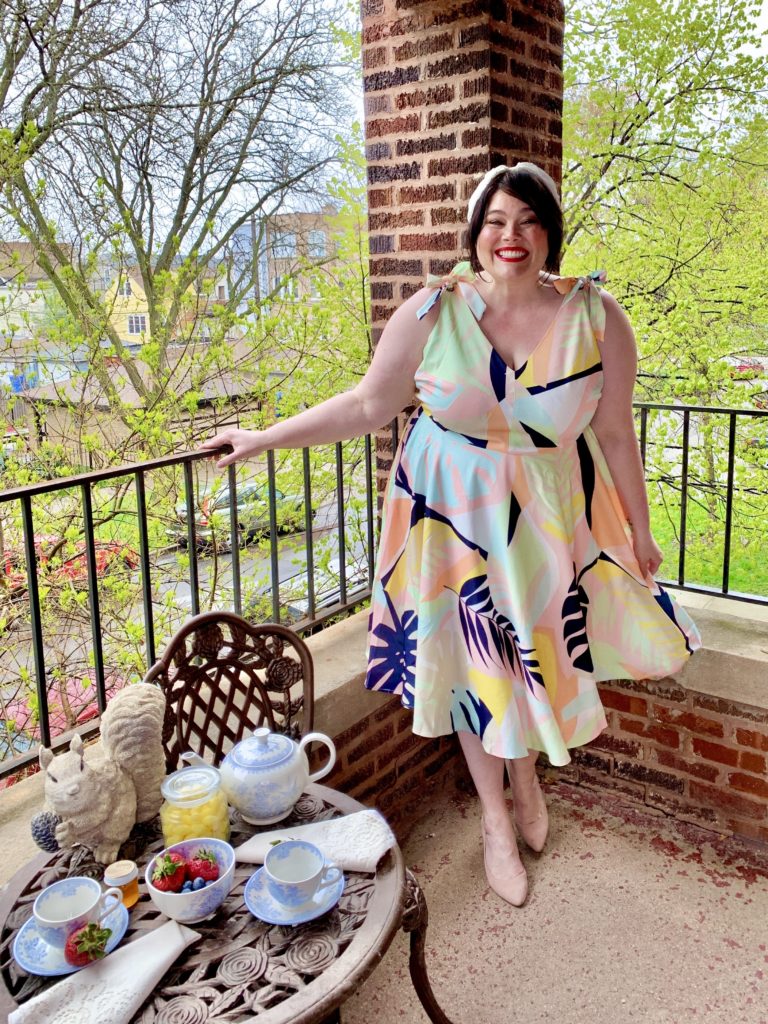 A happy, smiling plus size model in summery dress on a patio in Chicago.